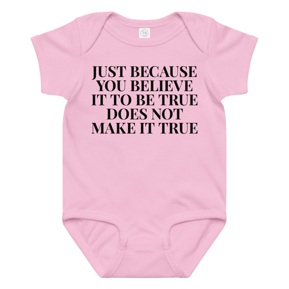 "Just because you believe it to be true does not make it true" printed on a pink baby jersey bodysuit laying on a flat surface amongst other clothes