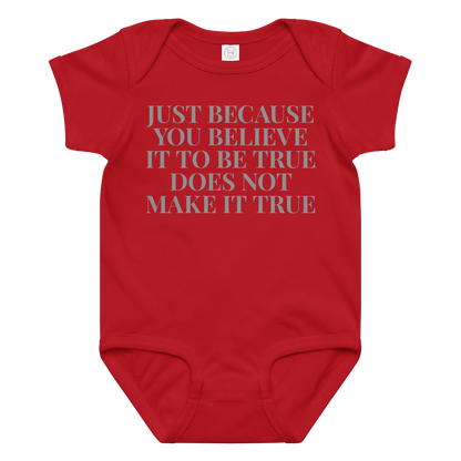 "Just because you believe it to be true does not make it true" printed on a red baby jersey bodysuit laying on a flat surface amongst other clothes
