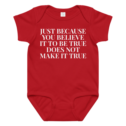 "Just because you believe it to be true does not make it true" printed on a red baby jersey bodysuit laying on a flat surface amongst other clothes