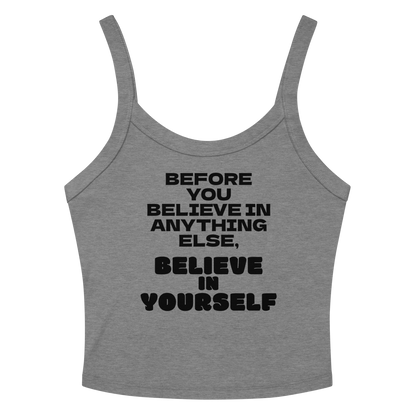 "Before you believe in anything else, believe in yourself" printed on a athletic heather women's micro-rib tanktop laying on a flat surface amongst sunglasses and shorts