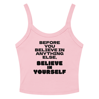 "Before you believe in anything else, believe in yourself" printed on a solid pink blend women's micro-rib tanktop laying on a flat surface amongst sunglasses and shorts