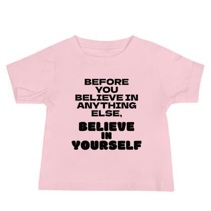 "Before you believe in anything else, believe in yourself" printed on a pink baby jersey short sleeve tee laying on a flat surface