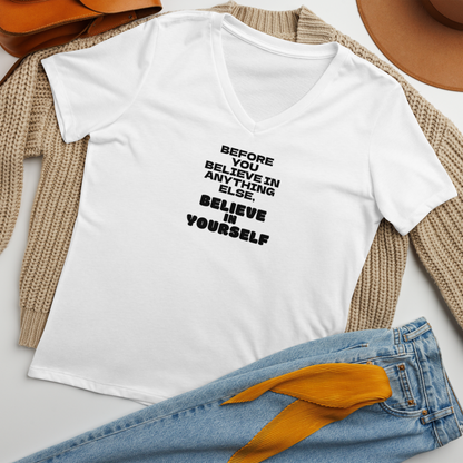"Before you believe in anything else, believe in yourself" printed on a solid white blend women's relaxed v-neck t-shirt laying on a flat surface amongst other clothes