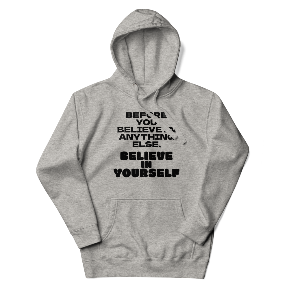 "Before you believe in anything else, believe in yourself" printed on a carbon grey unisex hoodie laying on a flat surface with the hood up