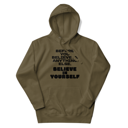 "Before you believe in anything else, believe in yourself" printed on a military green unisex hoodie laying on a flat surface with the hood up