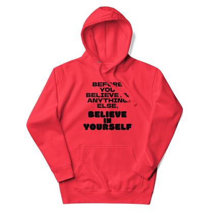 "Before you believe in anything else, believe in yourself" printed on a team red unisex hoodie laying on a flat surface with the hood up