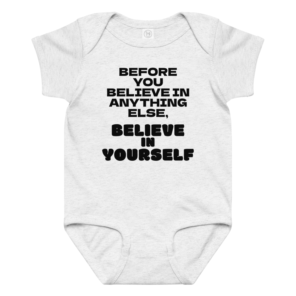 "Before you believe in anything else, believe in yourself" printed on a ash baby jersey bodysuit laying on a flat surface amongst other clothes