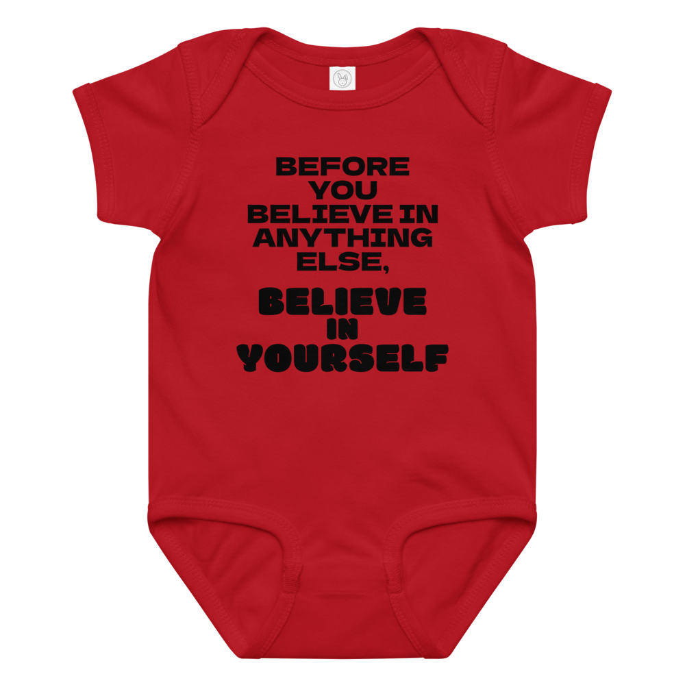 "Before you believe in anything else, believe in yourself" printed on a red baby jersey bodysuit laying on a flat surface amongst other clothes