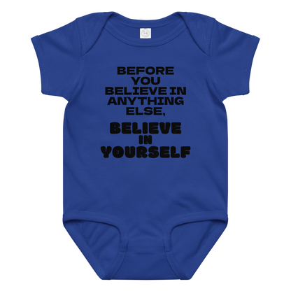 "Before you believe in anything else, believe in yourself" printed on a royal baby jersey bodysuit laying on a flat surface amongst other clothes