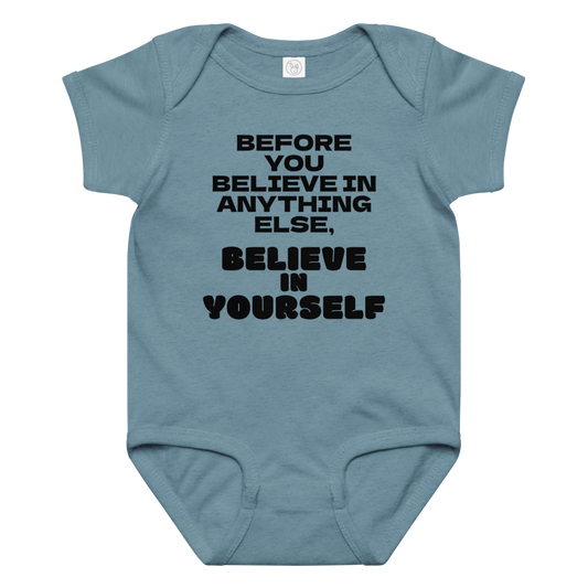 "Before you believe in anything else, believe in yourself" printed on a vintage indigo baby jersey bodysuit laying on a flat surface amongst other clothes