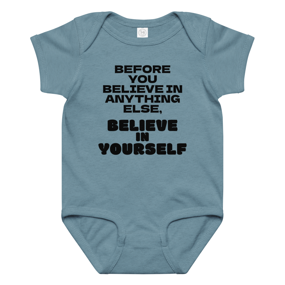 "Before you believe in anything else, believe in yourself" printed on a vintage indigo baby jersey bodysuit laying on a flat surface amongst other clothes