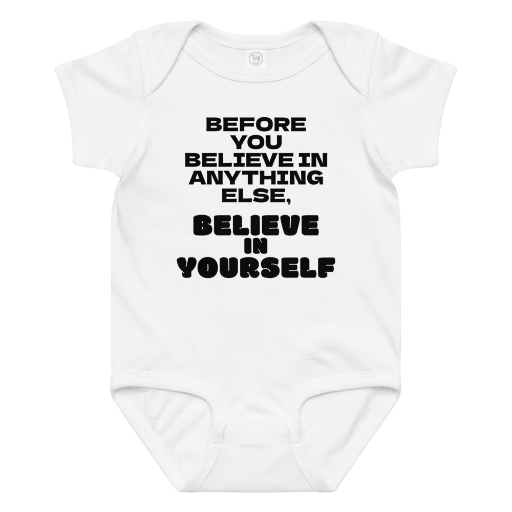 "Before you believe in anything else, believe in yourself" printed on a white baby jersey bodysuit laying on a flat surface amongst other clothes