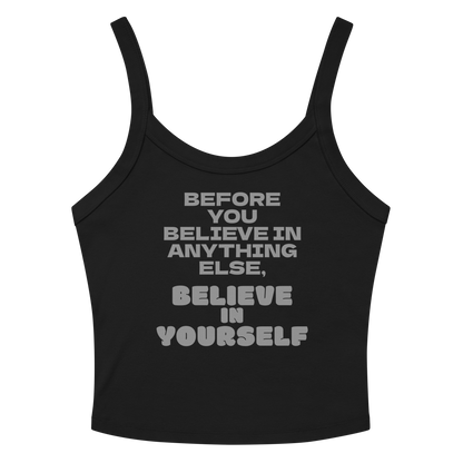 "Before you believe in anything else, believe in yourself" printed on a solid black blend women's micro-rib tanktop laying on a flat surface amongst sunglasses and shorts