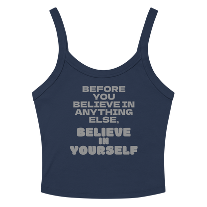 "Before you believe in anything else, believe in yourself" printed on a solid navy blend women's micro-rib tanktop laying on a flat surface amongst sunglasses and shorts