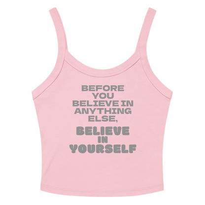 "Before you believe in anything else, believe in yourself" printed on a solid pink blend women's micro-rib tanktop laying on a flat surface amongst sunglasses and shorts