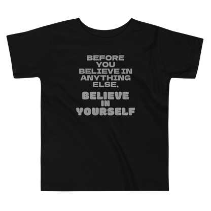 "Before you believe in anything else, believe in yourself" printed on a black toddler short sleeve tee laying on a flat surface