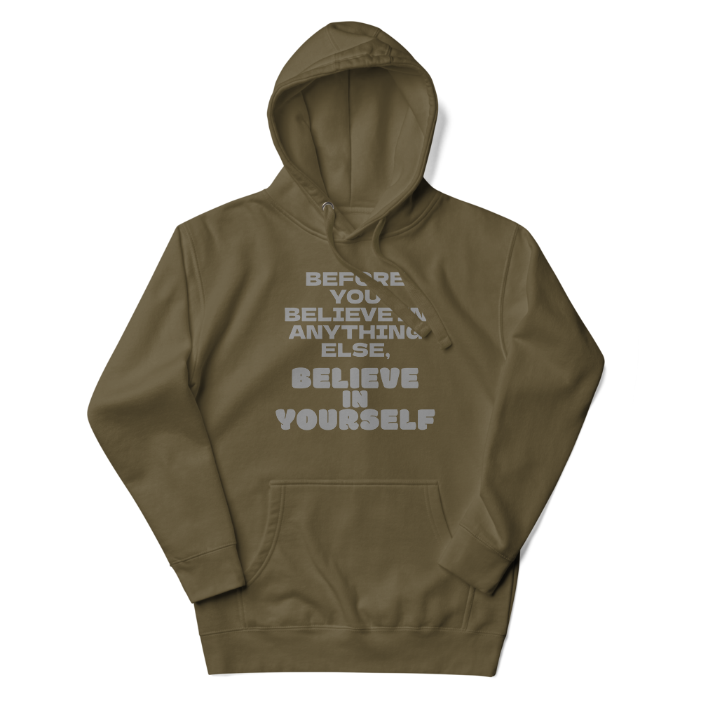 "Before you believe in anything else, believe in yourself" printed on a military green unisex hoodie laying on a flat surface with the hood up