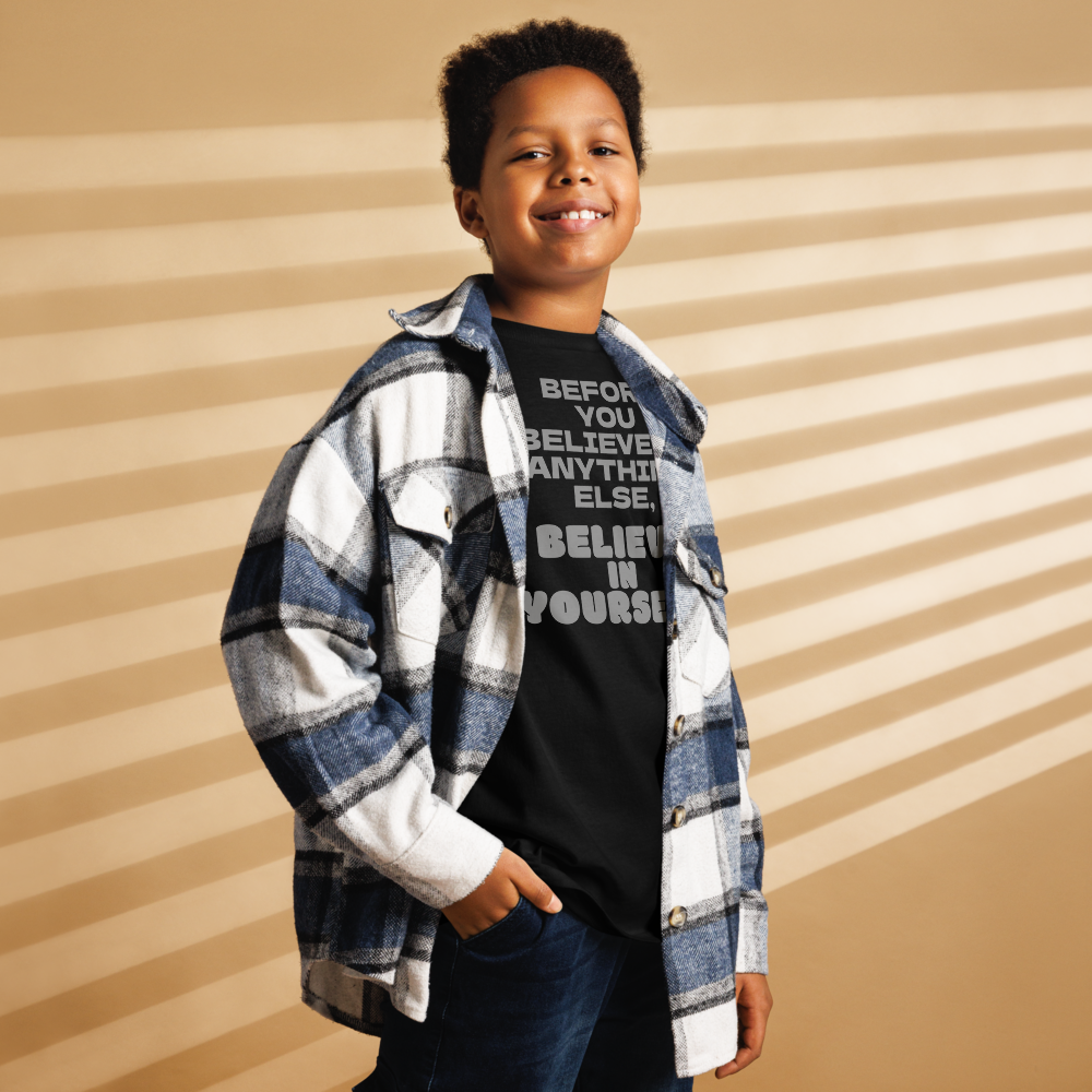 "Before you believe in anything else, believe in yourself" printed on a black youth classic tee worn by a male also wearing a jacket