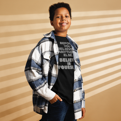 "Before you believe in anything else, believe in yourself" printed on a black youth classic tee worn by a male also wearing a jacket