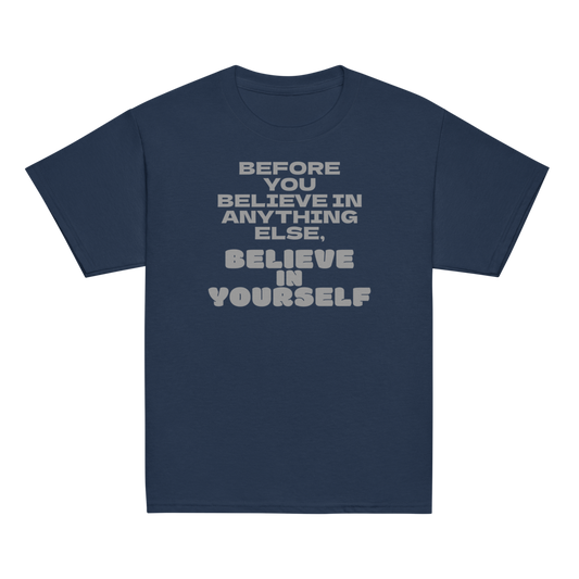 "Before you believe in anything else, believe in yourself" printed on a navy youth classic tee laying on a flat surface