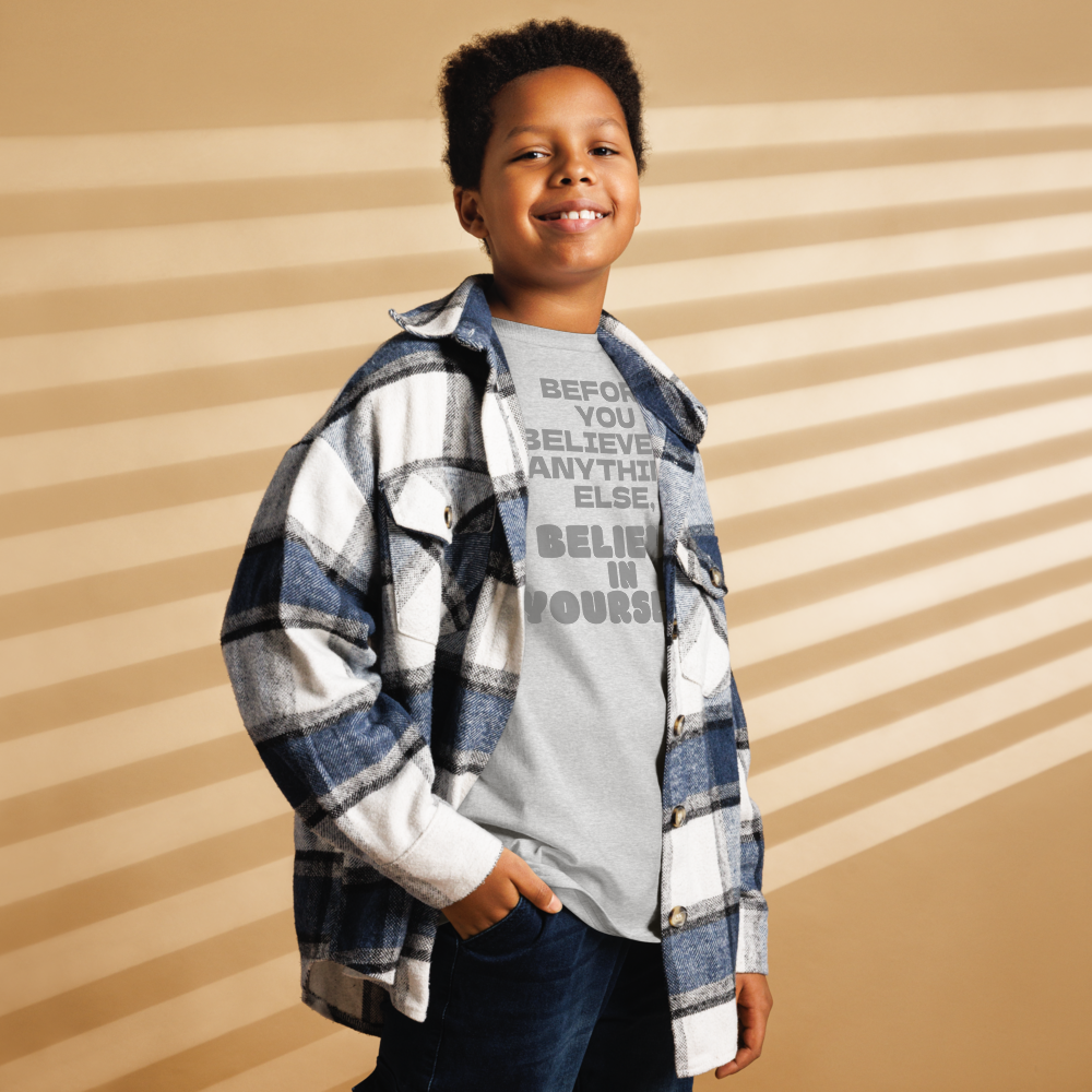 "Before you believe in anything else, believe in yourself" printed on a sport grey youth classic tee worn by a male also wearing a jacket