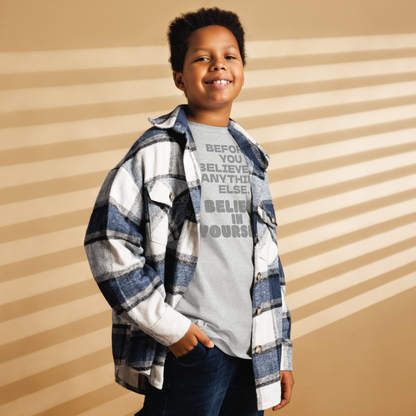 "Before you believe in anything else, believe in yourself" printed on a sport grey youth classic tee worn by a male also wearing a jacket