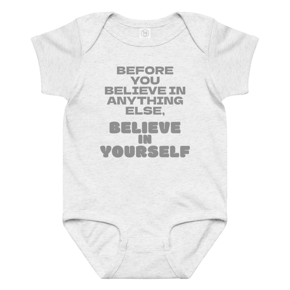 "Before you believe in anything else, believe in yourself" printed on a ash baby jersey bodysuit laying on a flat surface amongst other clothes