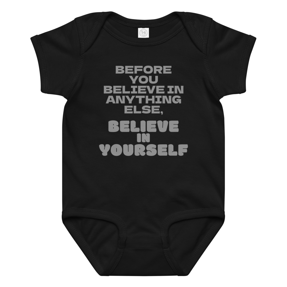 "Before you believe in anything else, believe in yourself" printed on a black baby jersey bodysuit laying on a flat surface amongst other clothes