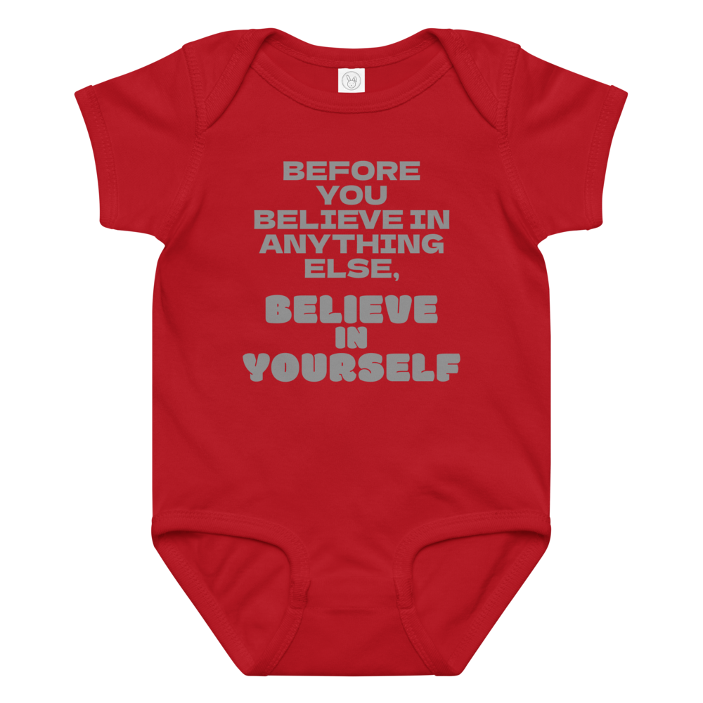 "Before you believe in anything else, believe in yourself" printed on a red baby jersey bodysuit laying on a flat surface amongst other clothes