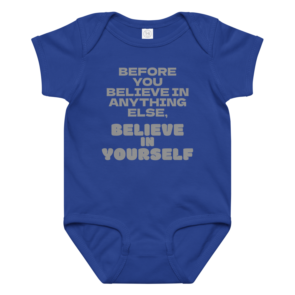 "Before you believe in anything else, believe in yourself" printed on a royal baby jersey bodysuit laying on a flat surface amongst other clothes