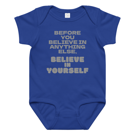 "Before you believe in anything else, believe in yourself" printed on a royal baby jersey bodysuit laying on a flat surface amongst other clothes