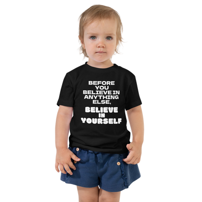 "Before you believe in anything else, believe in yourself" printed on a black toddler short sleeve tee worn by a female