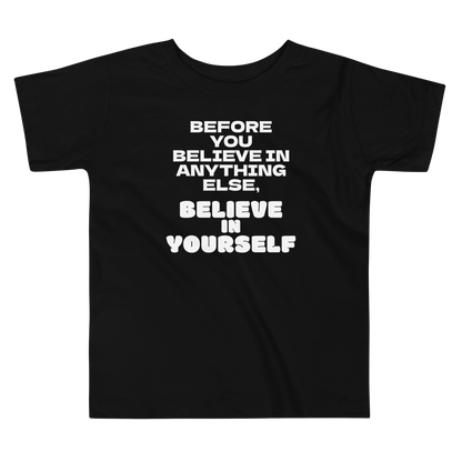 "Before you believe in anything else, believe in yourself" printed on a black toddler short sleeve tee laying on a flat surface