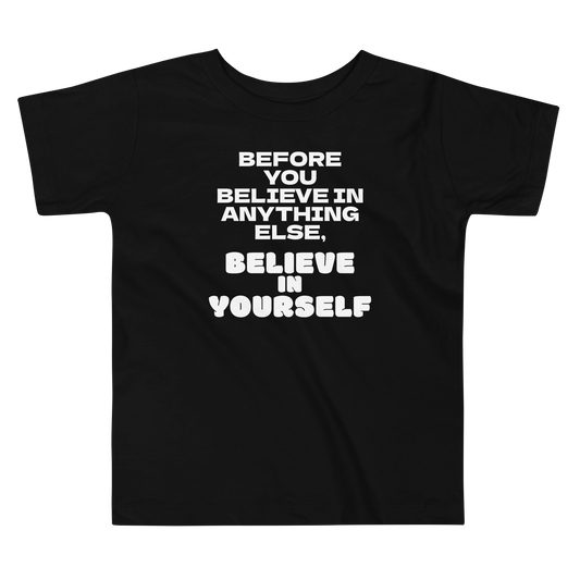 "Before you believe in anything else, believe in yourself" printed on a black toddler short sleeve tee laying on a flat surface