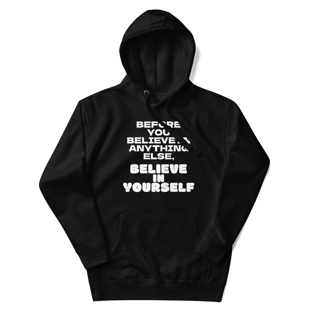 "Before you believe in anything else, believe in yourself" printed on a black unisex hoodie laying on a flat surface with the hood up
