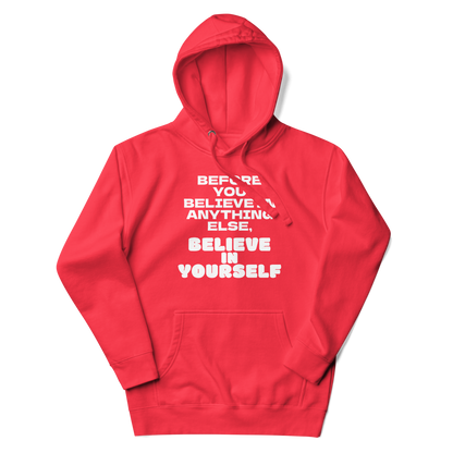 "Before you believe in anything else, believe in yourself" printed on a team red unisex hoodie laying on a flat surface with the hood up