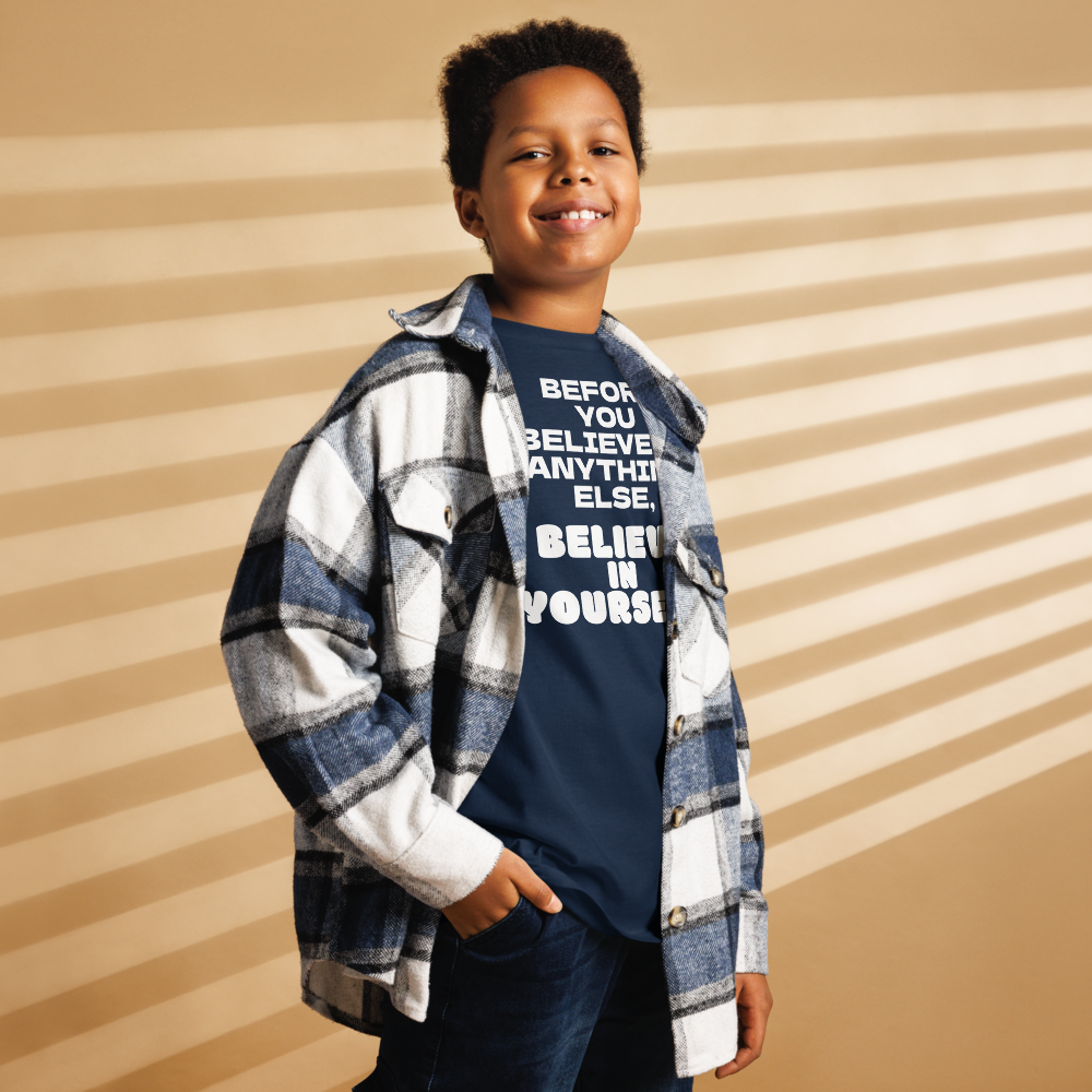 "Before you believe in anything else, believe in yourself" printed on a navy youth classic tee worn by a male also wearing a jacket
