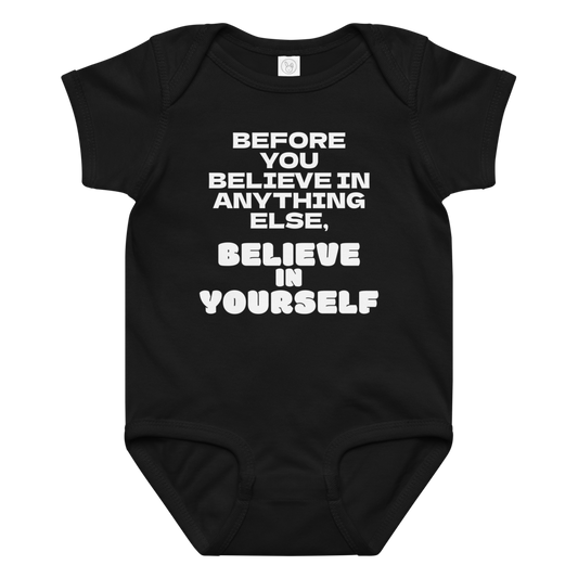 "Before you believe in anything else, believe in yourself" printed on a black baby jersey bodysuit laying on a flat surface amongst other clothes