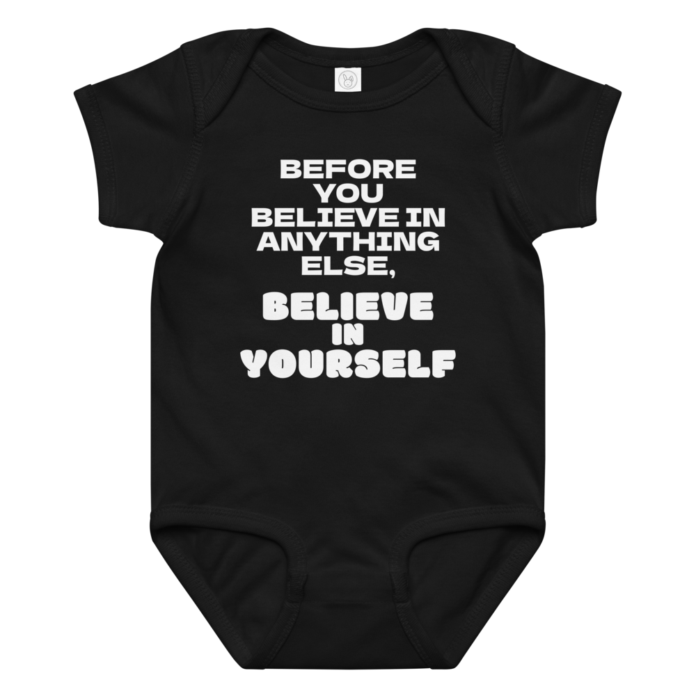 "Before you believe in anything else, believe in yourself" printed on a black baby jersey bodysuit laying on a flat surface amongst other clothes