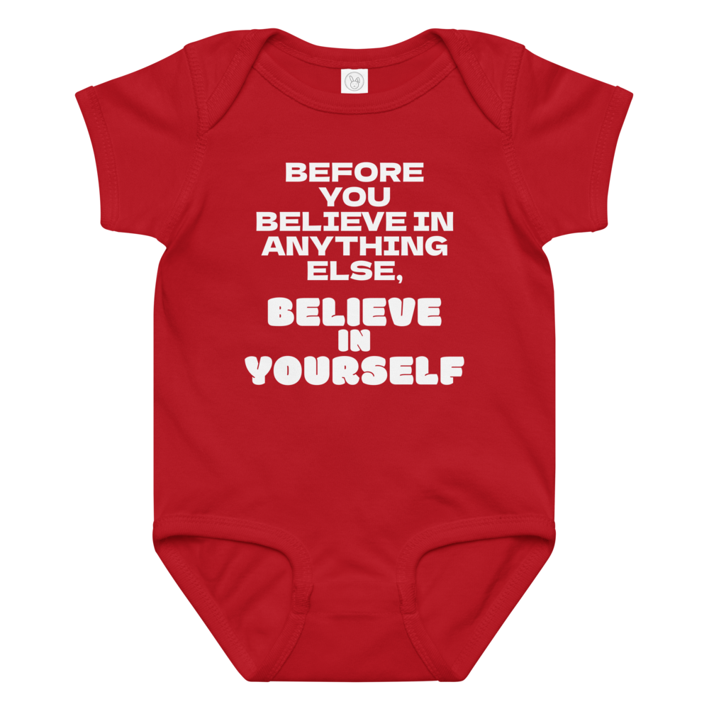 "Before you believe in anything else, believe in yourself" printed on a red baby jersey bodysuit laying on a flat surface amongst other clothes