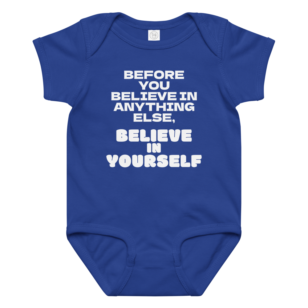 "Before you believe in anything else, believe in yourself" printed on a royal baby jersey bodysuit laying on a flat surface amongst other clothes