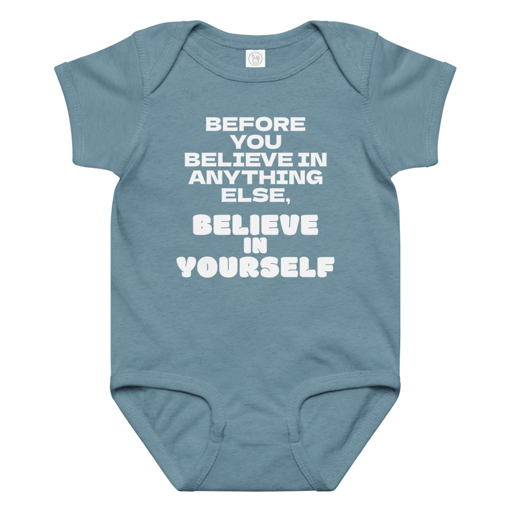 "Before you believe in anything else, believe in yourself" printed on a vintage indigo baby jersey bodysuit laying on a flat surface amongst other clothes