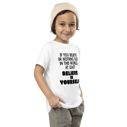 "If you believe in nothing else in this world, at least believe in yourself" printed on a white toddler short sleeve tee worn by a male who is also wearing a knit cap