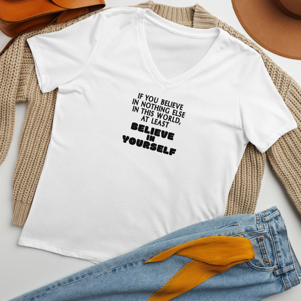 "If you believe in nothing else in this world, at least believe in yourself" printed on a solid white blend women's relaxed v-neck t-shirt laying on a flat surface amongst other clothes