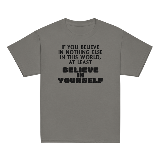 "If you believe in nothing else in this world, at least believe in yourself" printed on a charcoal youth classic tee laying on a flat surface