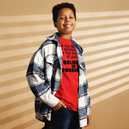 "If you believe in nothing else in this world, at least believe in yourself" printed on a red youth classic tee worn by a male also wearing a jacket