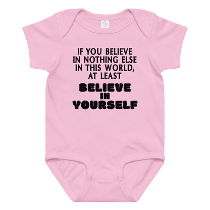 "If you believe in nothing else in this world, at least believe in yourself" printed on a pink baby jersey bodysuit laying on a flat surface amongst other clothes