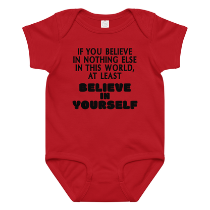 "If you believe in nothing else in this world, at least believe in yourself" printed on a red baby jersey bodysuit laying on a flat surface amongst other clothes