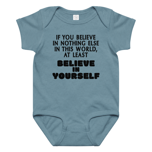 "If you believe in nothing else in this world, at least believe in yourself" printed on a vintage indigo baby jersey bodysuit laying on a flat surface amongst other clothes