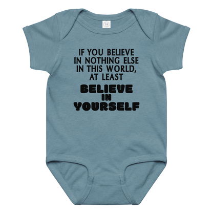 "If you believe in nothing else in this world, at least believe in yourself" printed on a vintage indigo baby jersey bodysuit laying on a flat surface amongst other clothes